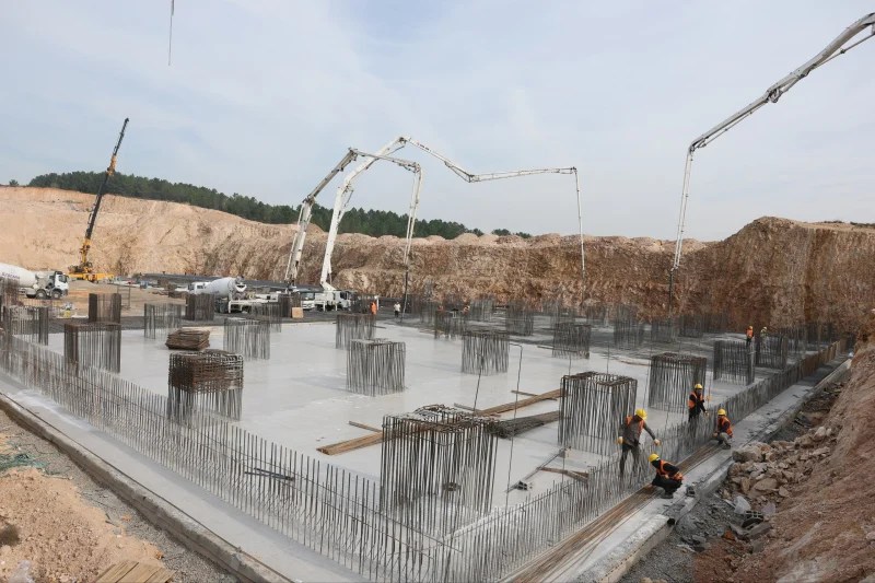 Çayırova Devlet Hastanesi inşaat alanında temel beton dökme işlemi gerçekleştiriliyor, işçiler çalışıyor.