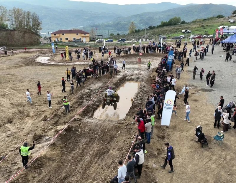 Gölcük'te düzenlenen 2. Geleneksel ATV Yarışları sırasında bir ATV'nin su ve çamur dolu parkurda yarıştığı, etrafında kalabalık bir seyirci grubu olduğu bir an.