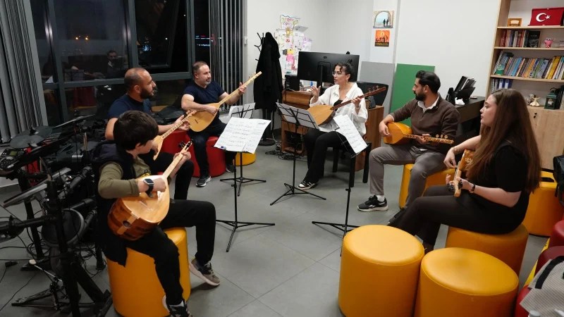 Bir grup müzisyen, bağlama eğitimi için bir araya gelerek çalıyor ve nota çalışıyor.