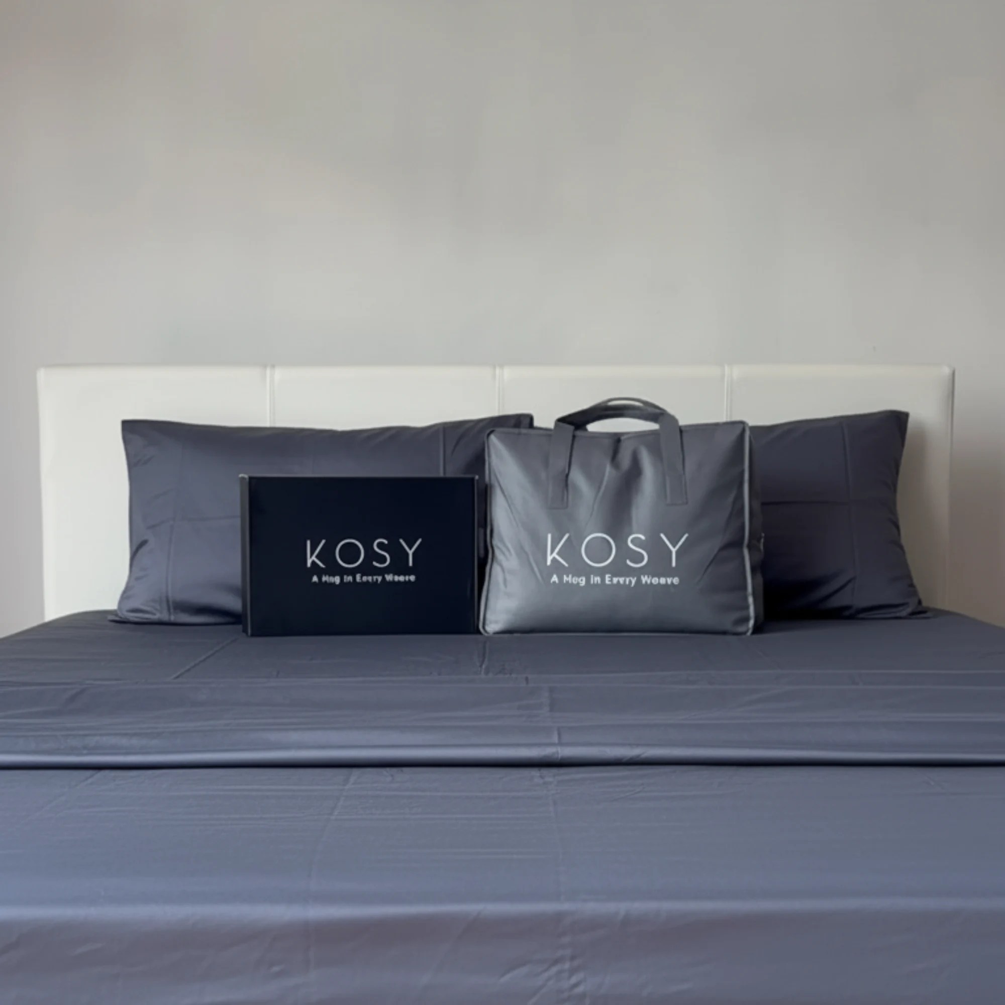Kosy bedding set with grey bamboo sheets, pillowcases, and packaging displayed neatly on a bed.