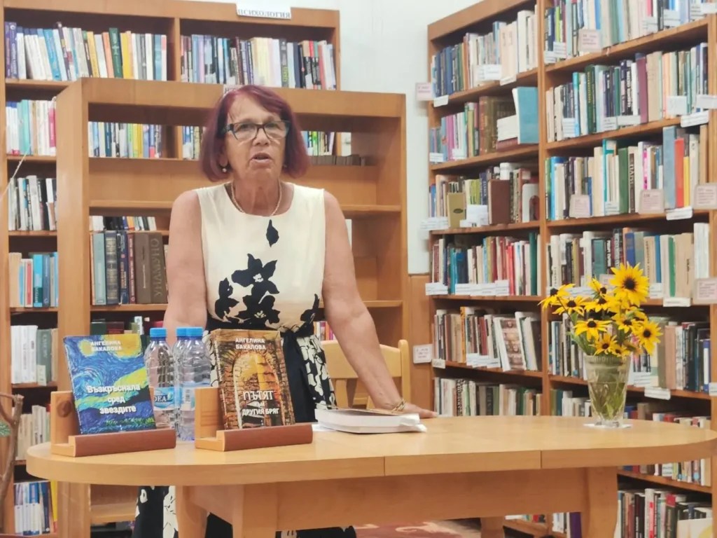 Авторка представя книги в библиотека, заобиколена от книги и цветя. Интерактивно събитие за литература.