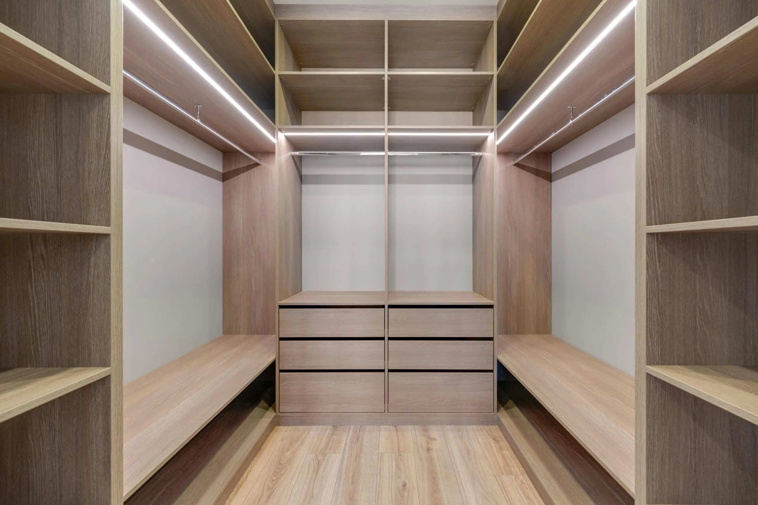 Closet de madera con cajones centrales, bancos laterales y estanterías iluminadas