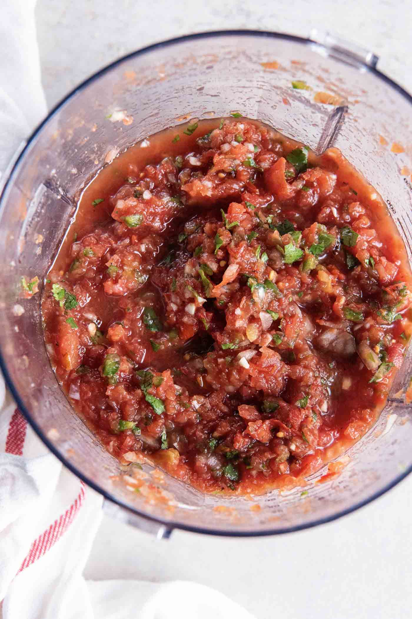 The BEST Homemade Salsa Recipe! This restaurant-style salsa is easy to make with simple ingredients. It has the best fresh flavor and is a perfect appetizer with tortilla chips! Homemade salsa in food processor.