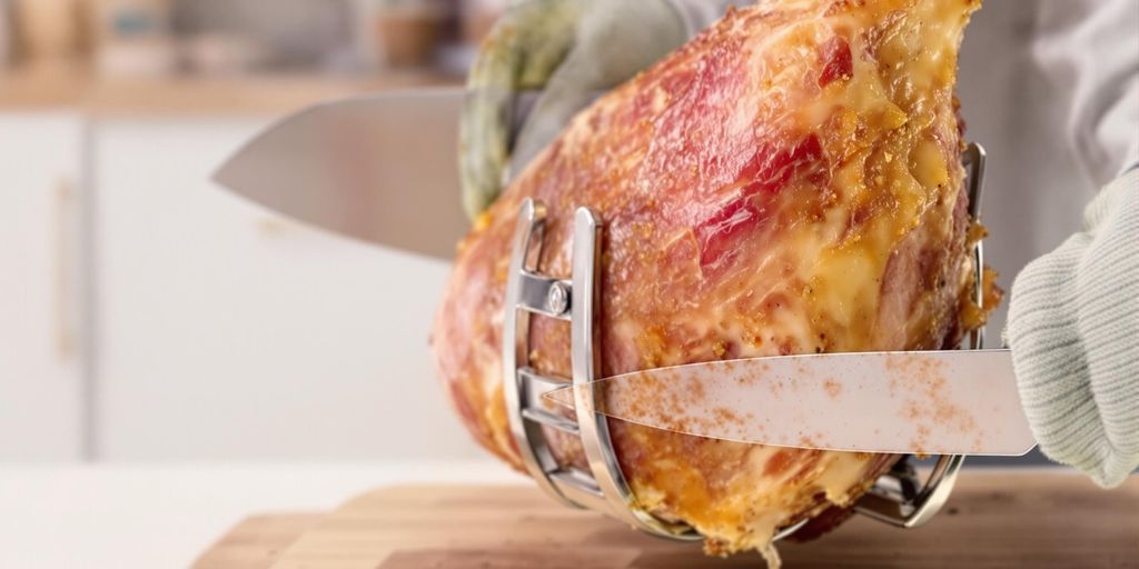 Person holding ham with knife in safe position.