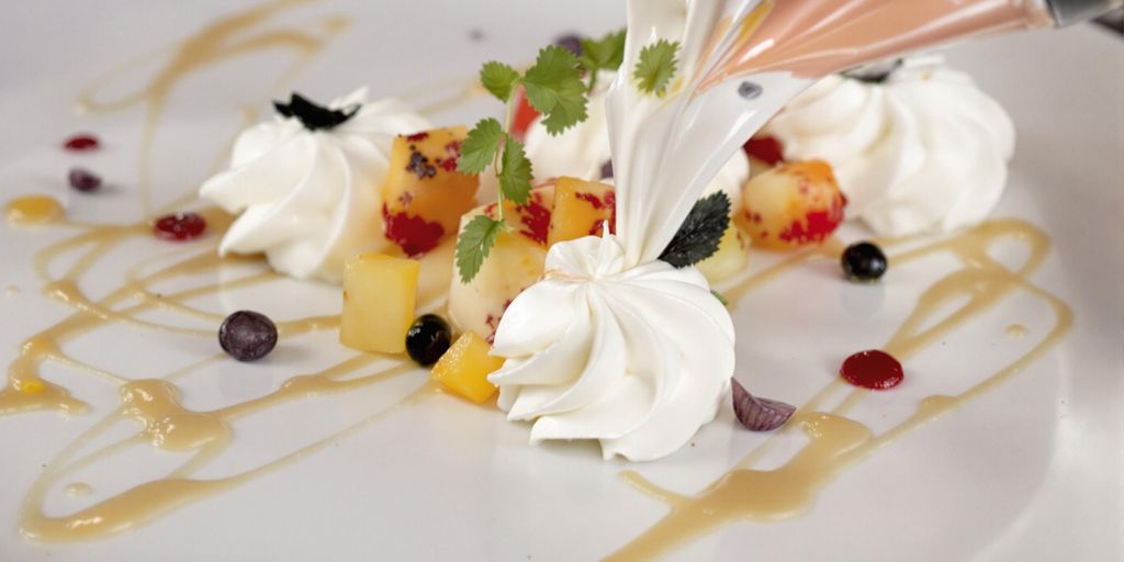 Elegant dessert with whipped cream and fruit garnishes.
