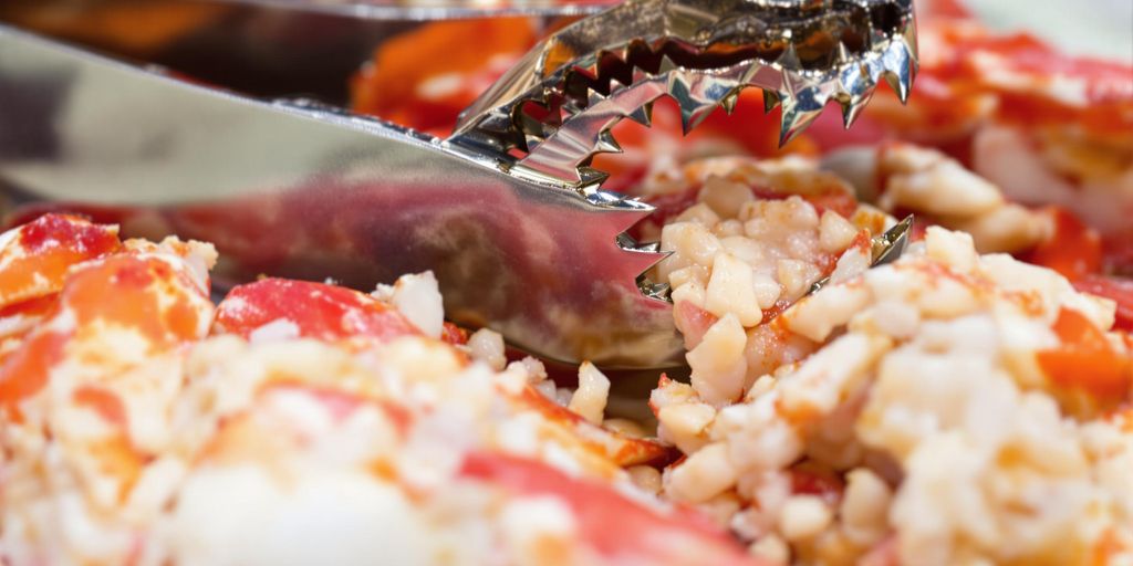 Crab cracker tool with fresh crab legs and meat.