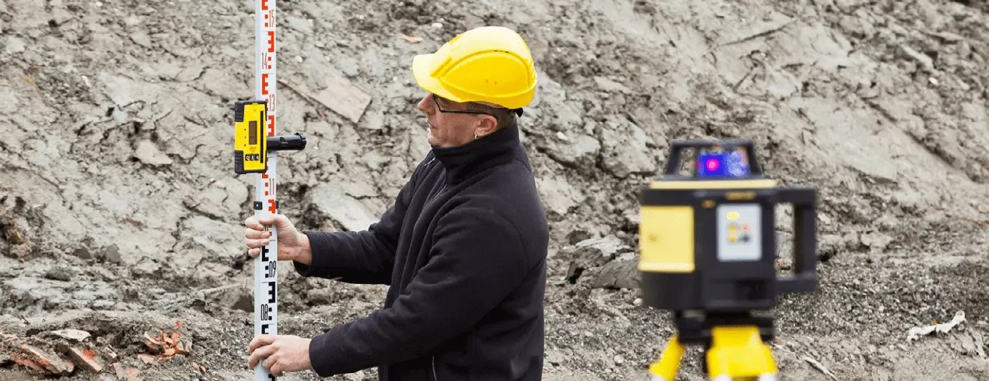 Surveyor using equipment on construction site.