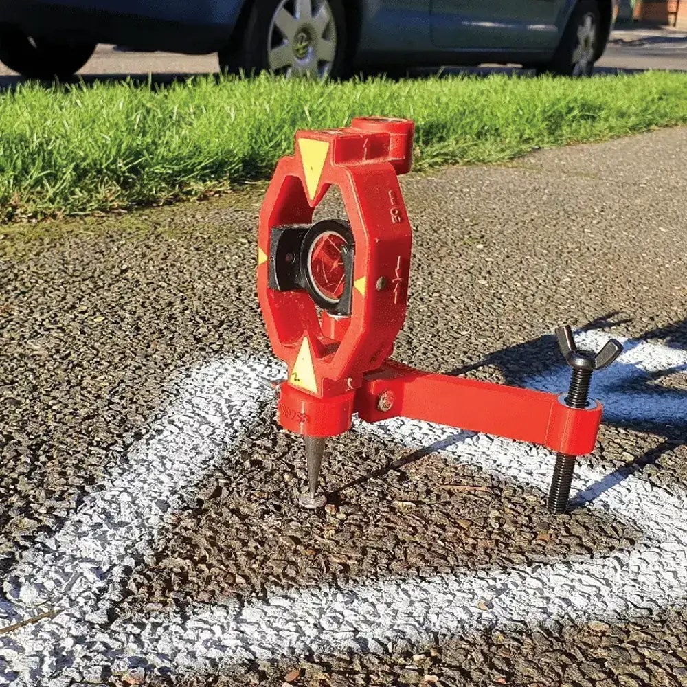 Surveying tool on pavement with painted markings.
