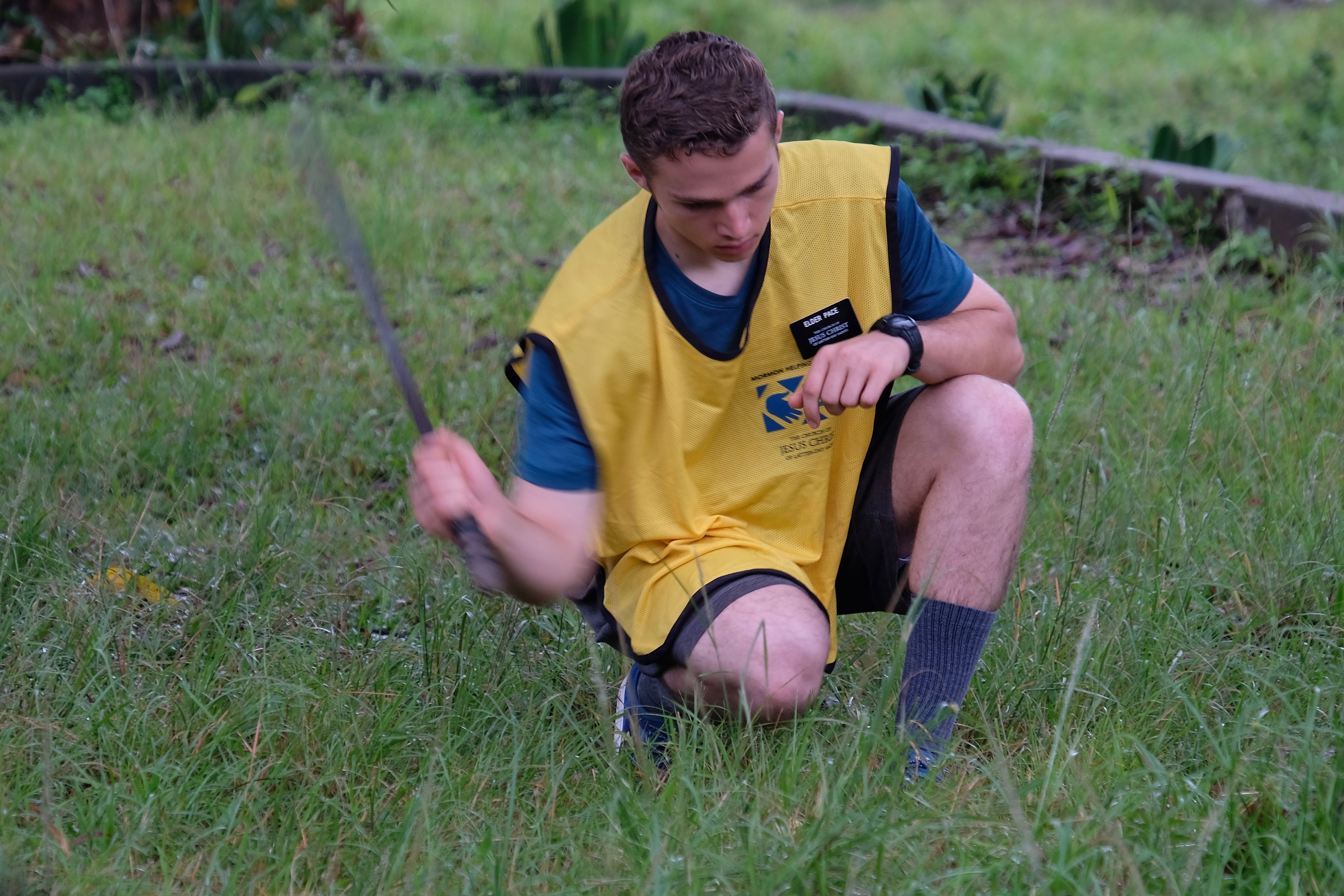 Elder Pace learning to cut weeds with a machete