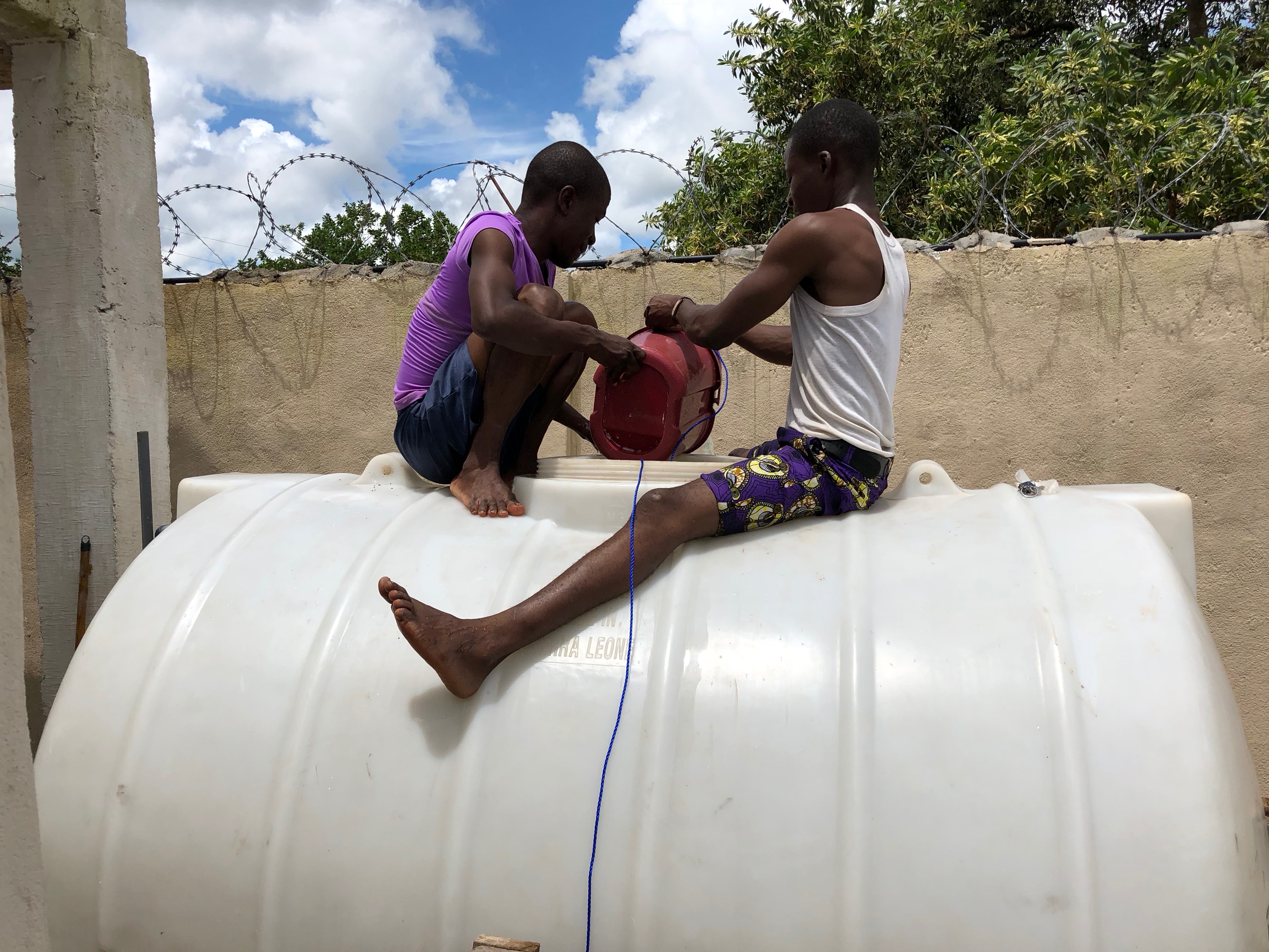 Max (left) and Dass (right) emptying water from the ground tank