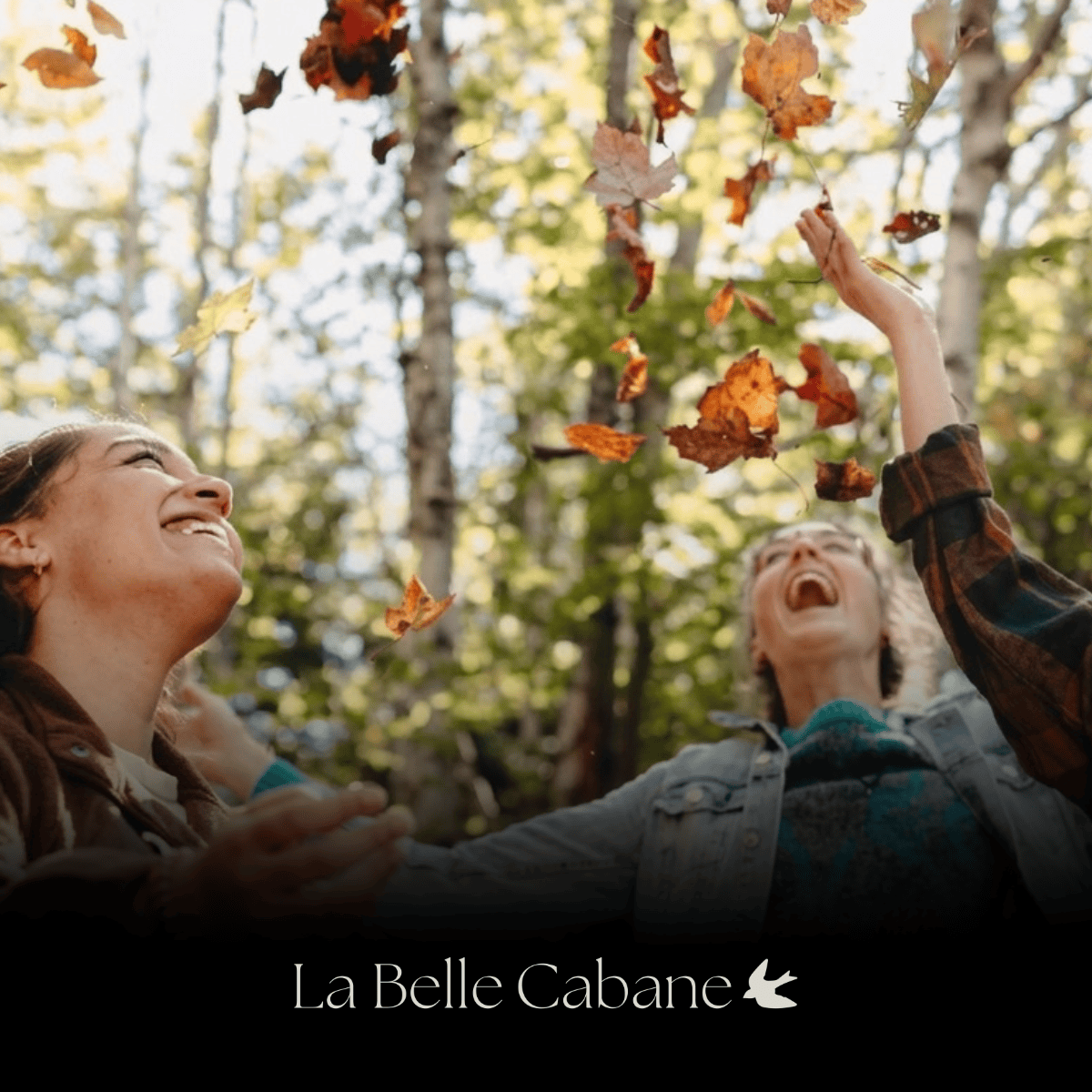 Two friends laughing and tossing autumn leaves in the forest at La Belle Cabane on the Kingston Peninsula, near Saint John, NB