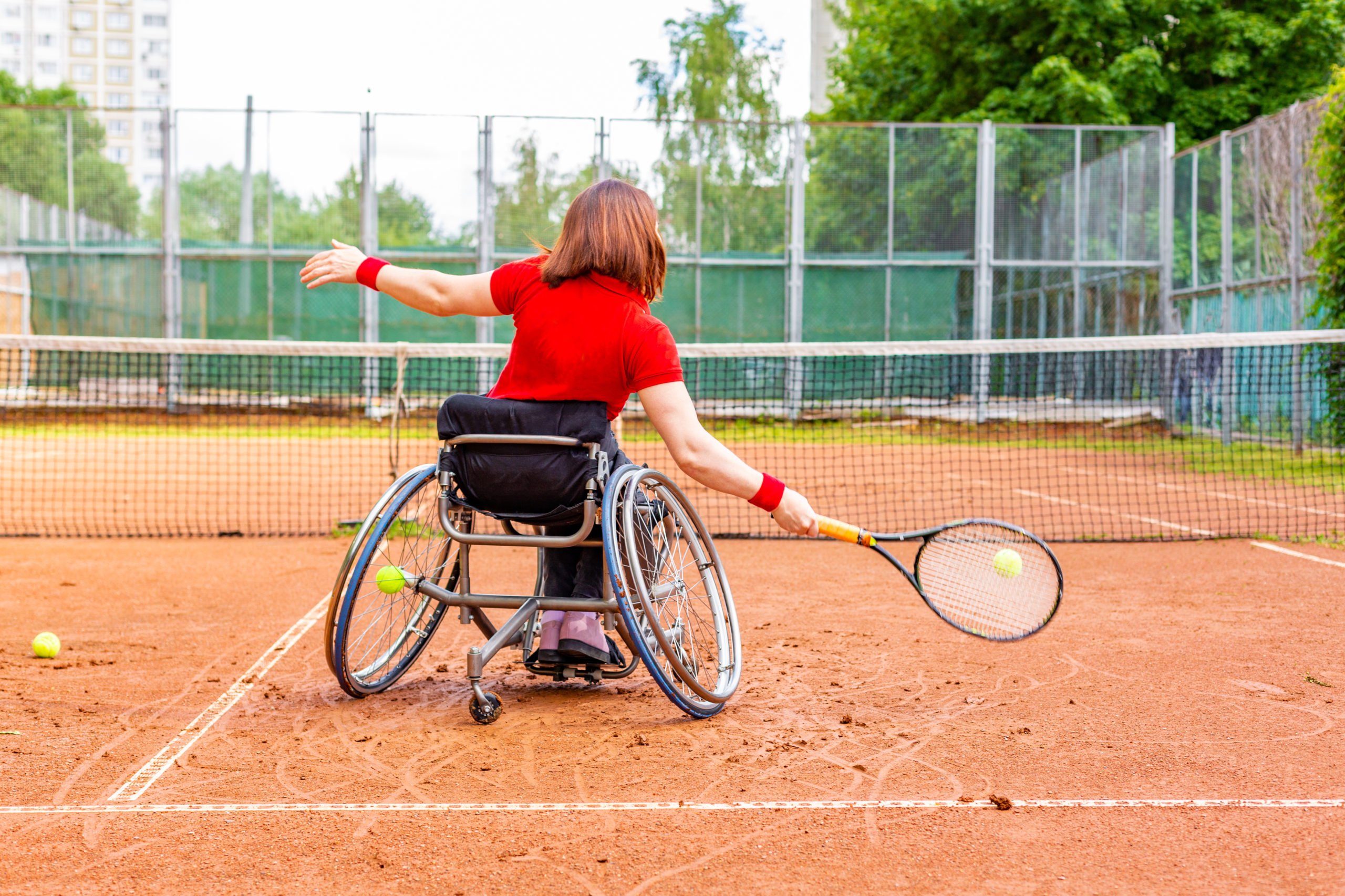 Jeune femme en fauteuil roulant jouant au tennis sur un court de tennis.