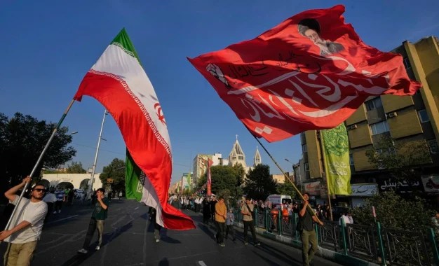 iran Unos hombres ondean banderas de Irán y una bandera roja con el retrato del difunto Líder Supremo, el ayatolá Alí Jamenei, durante una celebración callejera con motivo del nacimiento del profeta Mahoma en Teherán, Irán, el domingo 30 de agosto de 2026. Al fondo se ve la catedral armenia de San Sarkis. Ap