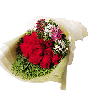A vibrant bouquet of red roses and mixed flowers wrapped in cream paper.