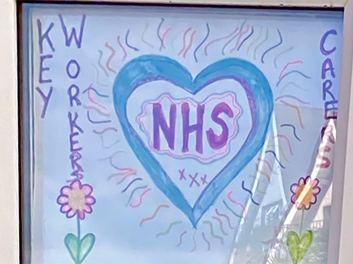 This is a big blue and purple heart shape and inside it there's a cloud-like shape and the letters NHS, The heart shape has blue and purple streamers of colour coming out from it and one one side of the page, in vertical lettering it says Kay Workers followed by a flower and on the other side it says Carers followed by a flower.