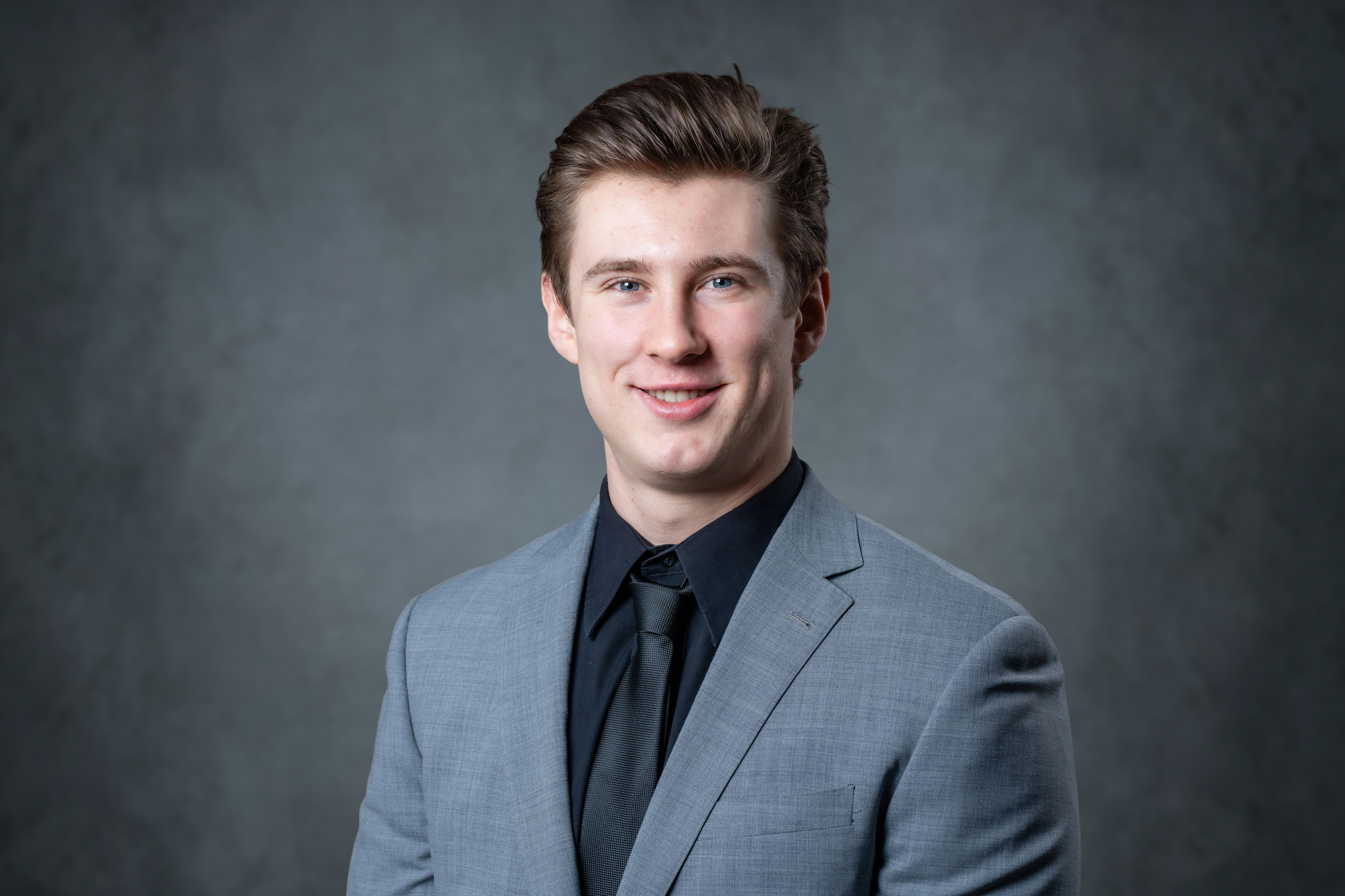 A young man in a suit, likely for a professional profile picture or stock photo. The young man has short, dark blond hair ...