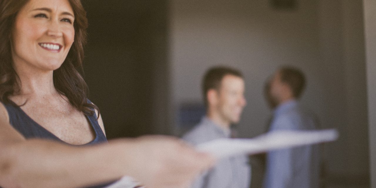 a woman holding out a sheet of paper