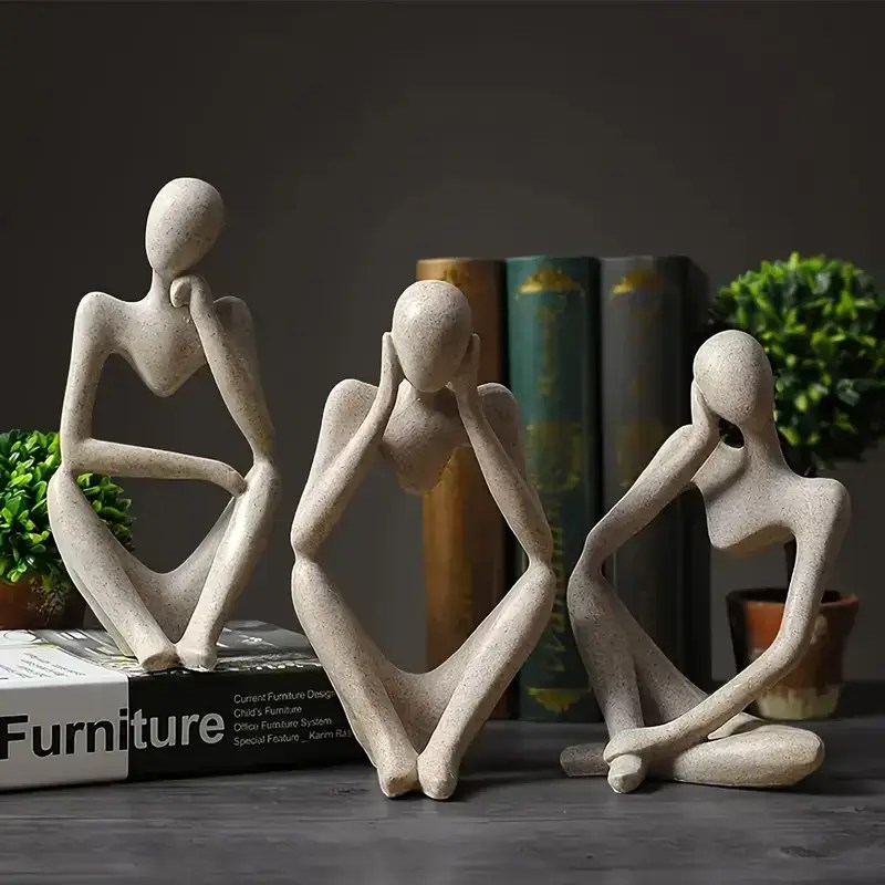 Decorative abstract thinker statues arranged on shelf with books and plants, stylish modern home decor.