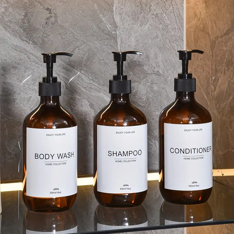 Set of three amber pump bottles labeled body wash, shampoo, and conditioner, stylish bathroom organisation.