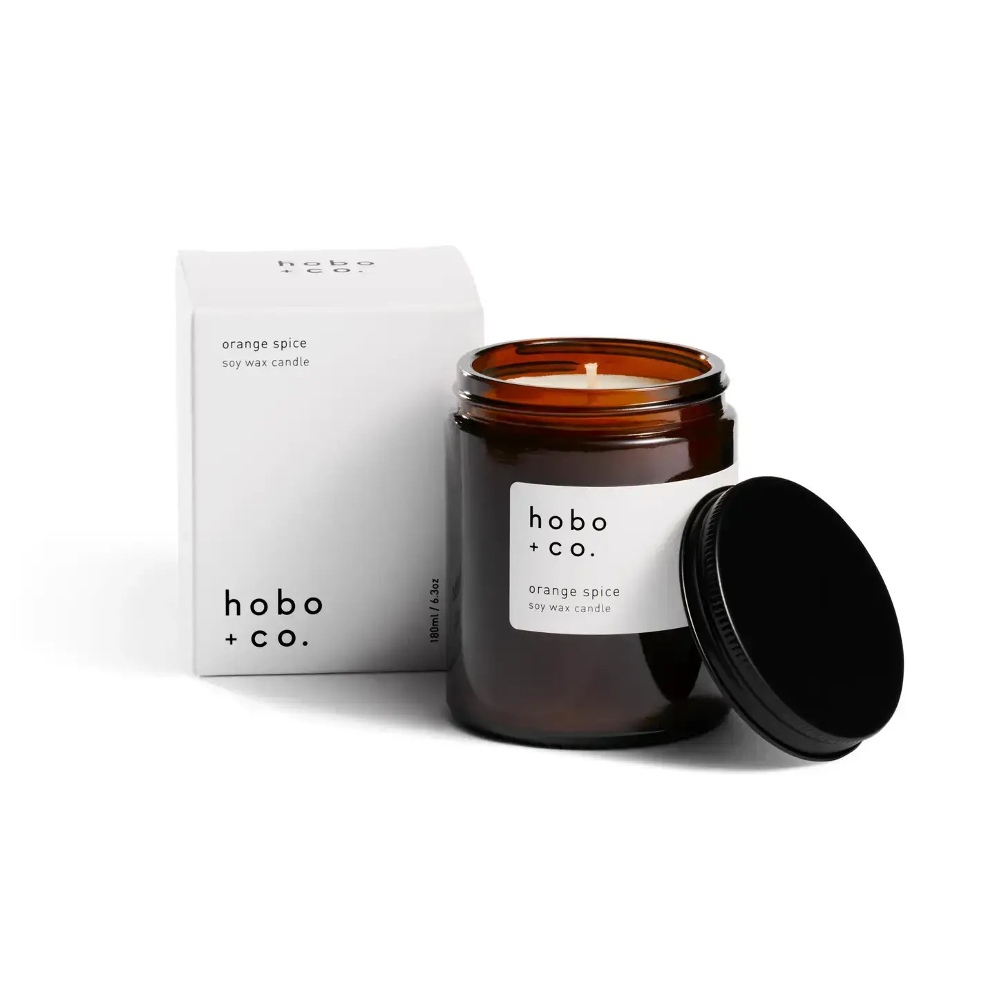 Orange Spice soy wax candle in amber glass jar with black lid and minimalist packaging.