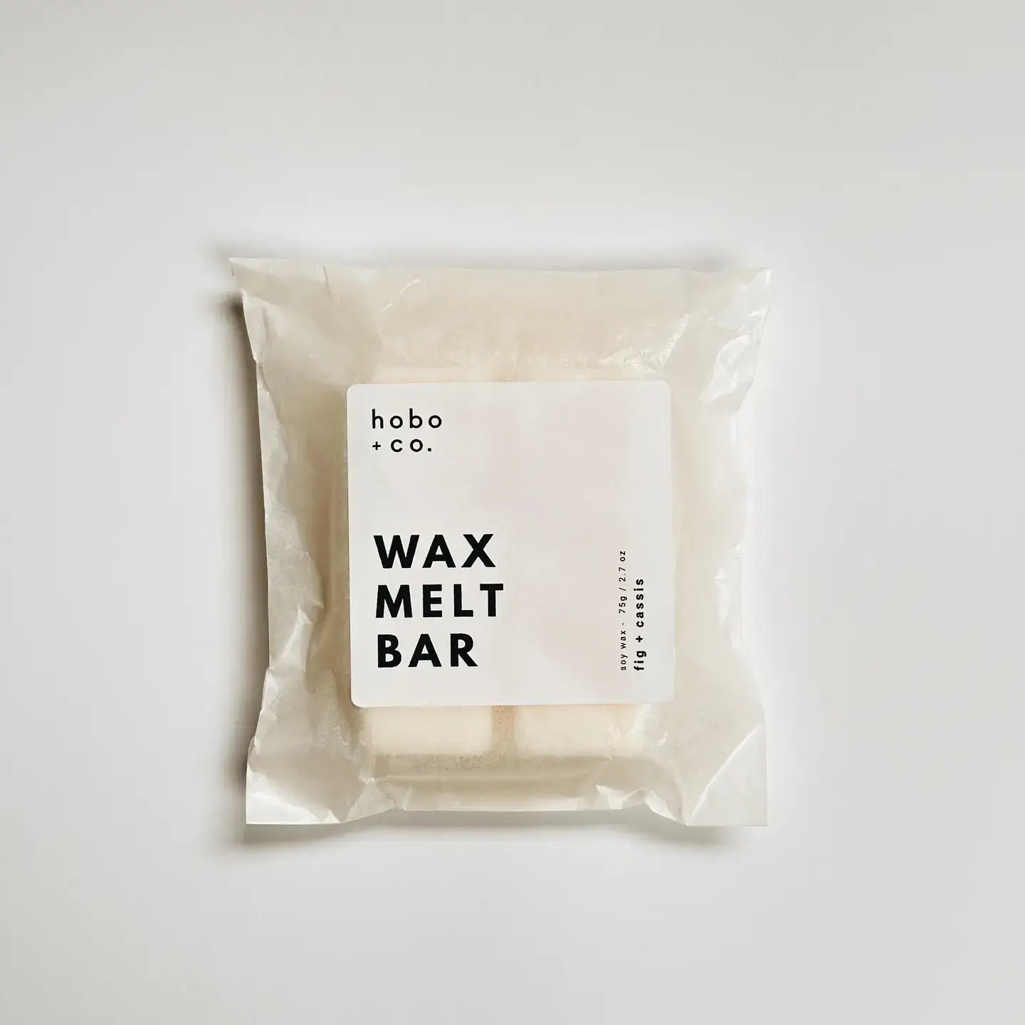A white wax melt bar is packaged in a clear plastic wrapper with a white label displaying the product name.