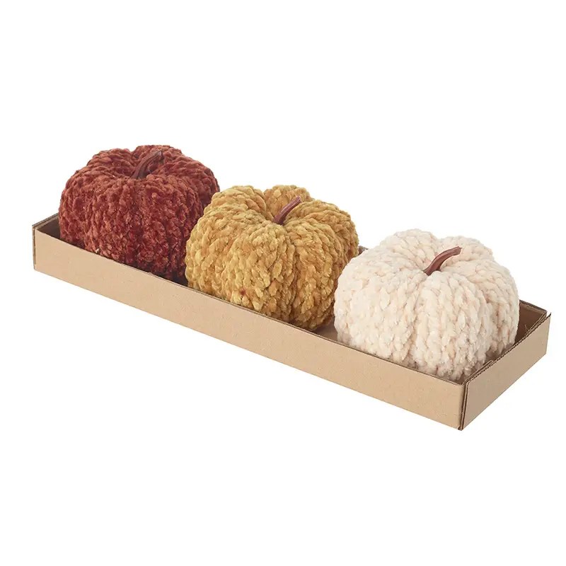 Set of three chunky knitted pumpkins in autumn colours on display tray