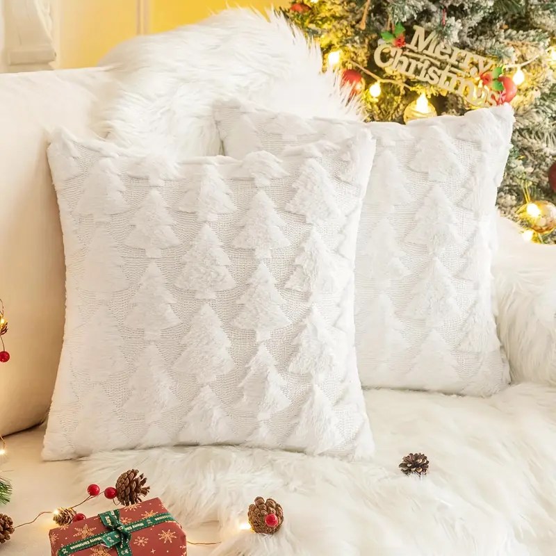 Pair of white fluffy Christmas tree cushions on sofa with Christmas decorations and lights.