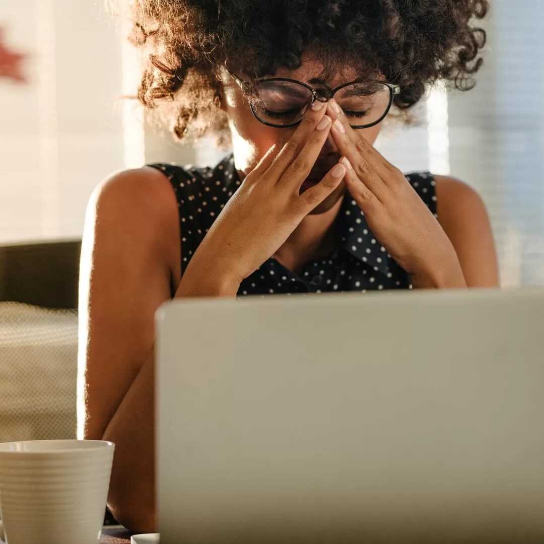 woman with news anxiety holding face in front of open laptop