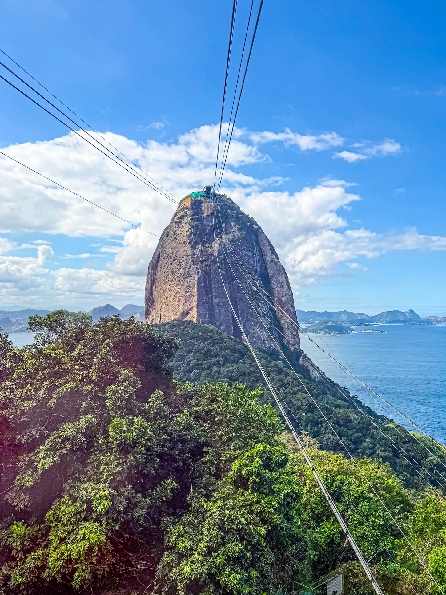 Cable car ascending Sugarloaf Mountain with scenic ocean views.