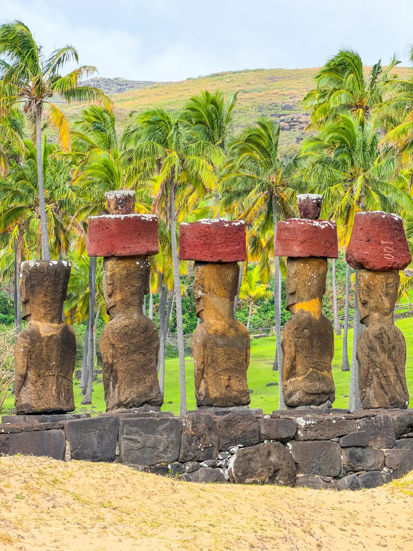 Easter Island Moai statues with lush palm trees in the background.