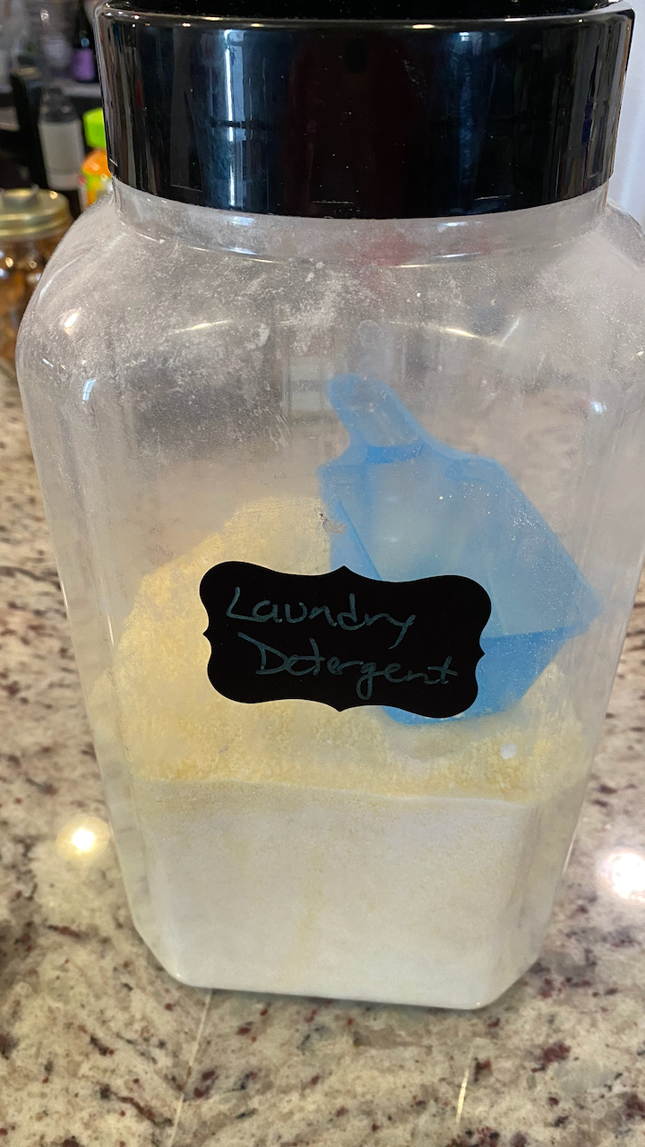 Container of final product with a blue scoop inside, black label on the front.