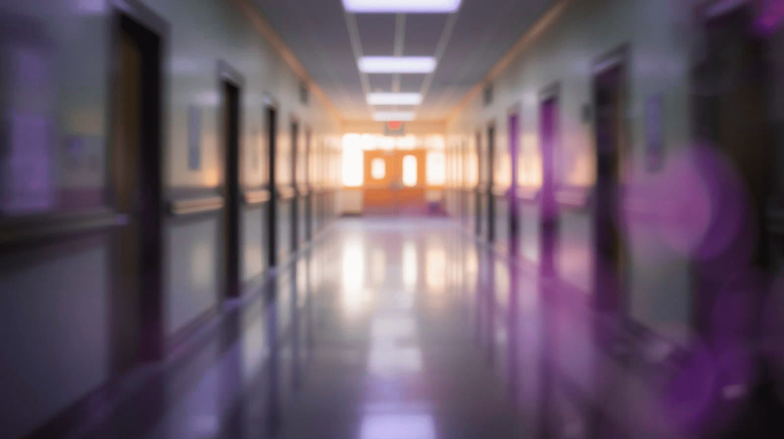 A quiet school hallway with classroom doors closed and warm light glowing through the windows, soft natural lighting, shallow depth of field, calm reflective atmosphere