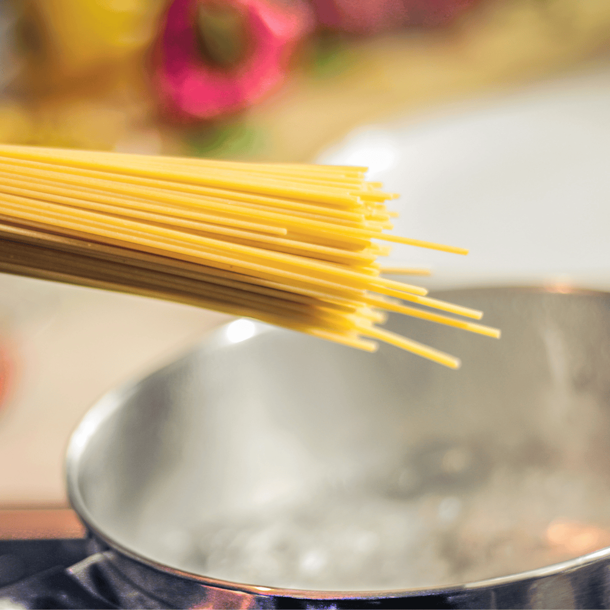 Spaghetti noodles dangled over a boiling pot of water