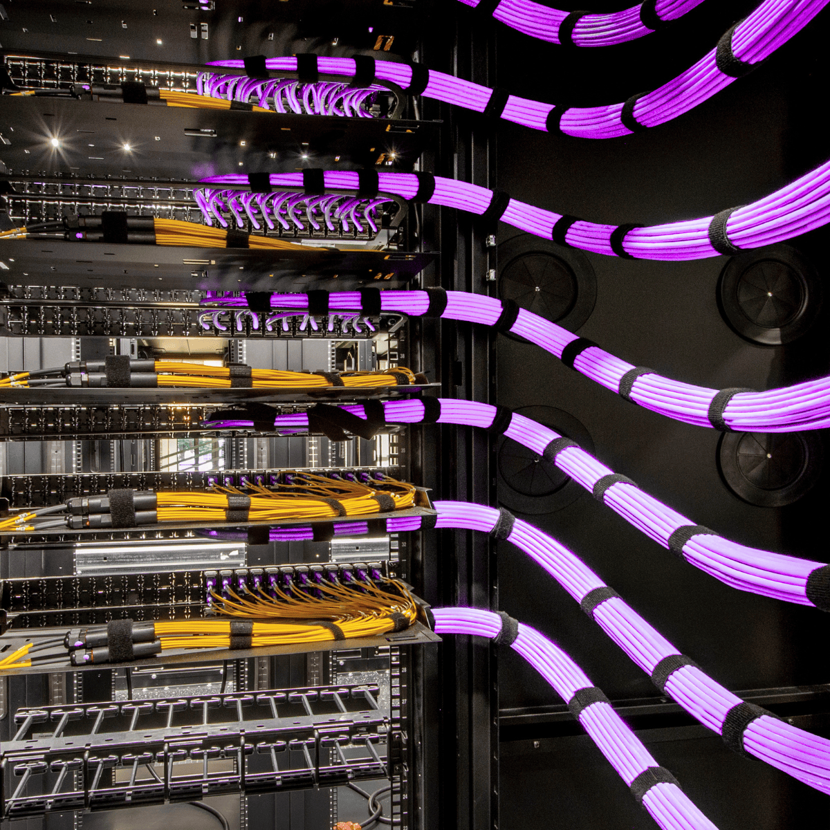 A server rack in an empty room with rows of green status lights glowing.