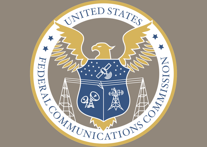 The FCC Seal. Text reads "United States Federal Communications Commission. There's an eagle in front of a badge. Across the badge are tellecommunication wires, and inside it are satellites, receivers, and an antenna.
