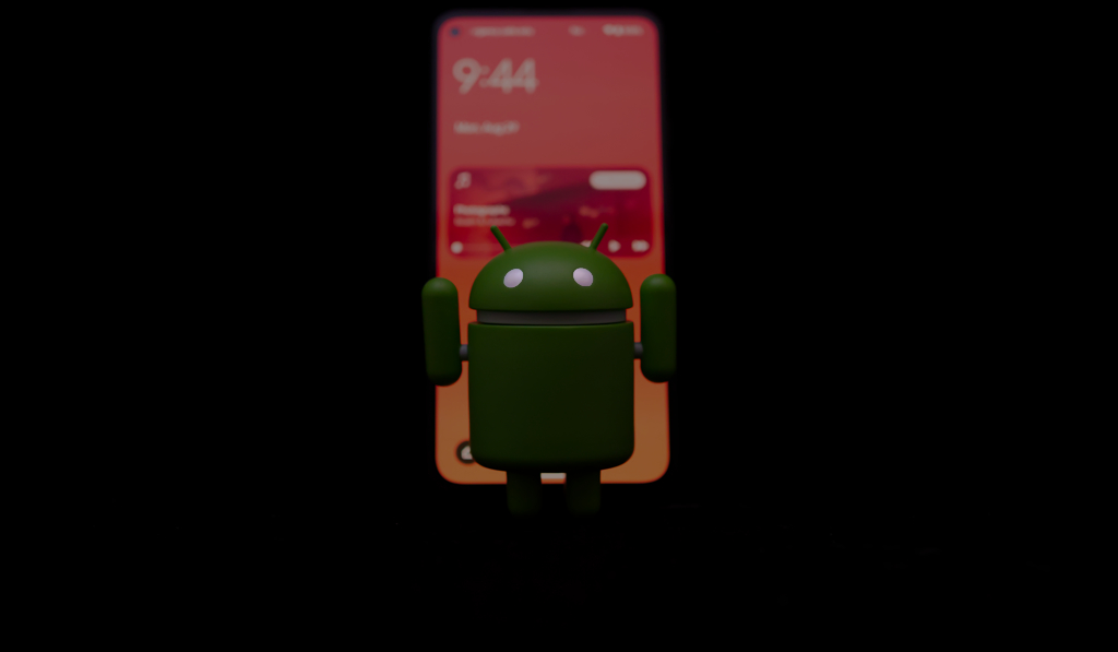 The Bugdroid Android mascot in front of a Google Pixel 5a