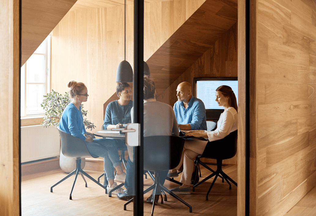 Five people seating at a table inside a conference room.
