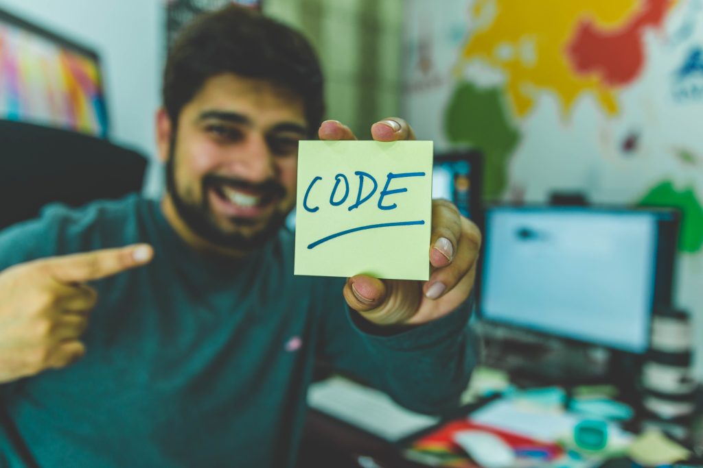 How Does A C Program Work Internally? A picture of someone holding up a yellow not which says "code" on it