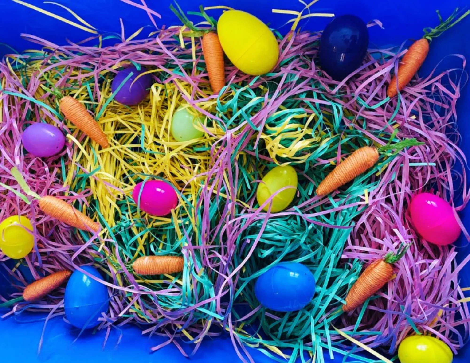 simple easter sensory bin with paper easter grass, yarn wrapped carrots and plastic eggs