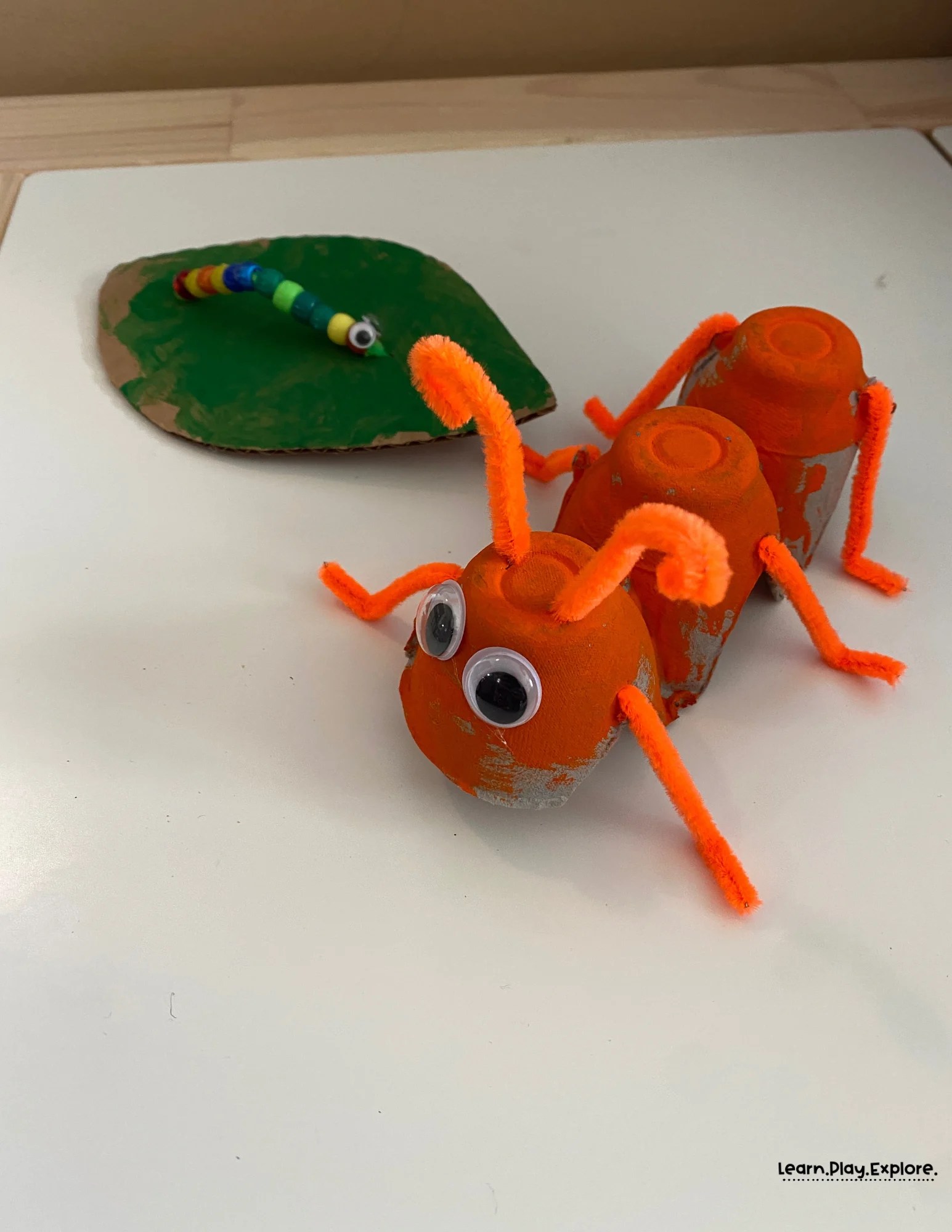 orange and project and beaded caterpillar on a green painted cardboard leaf