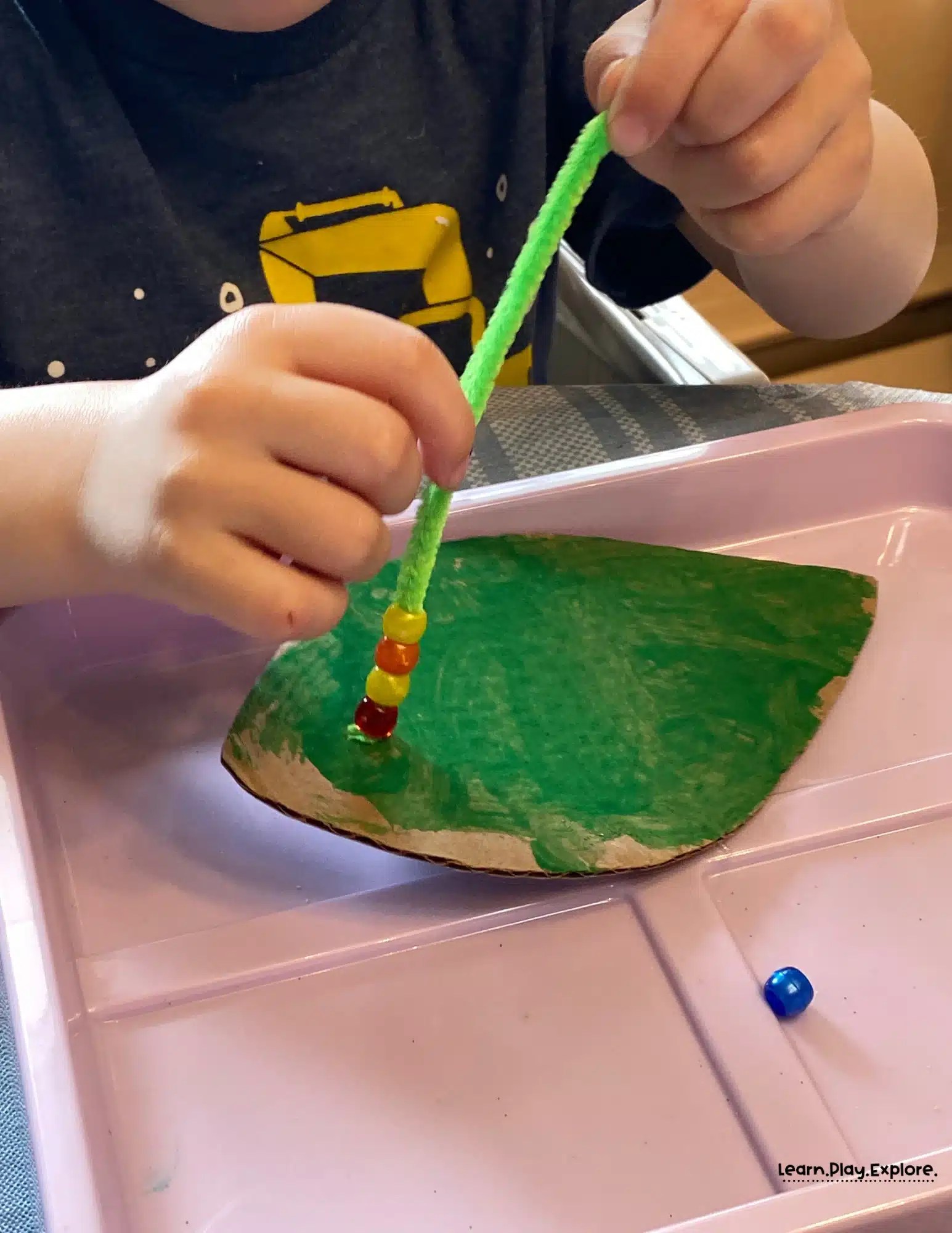 toddler stringing beads on pipecleaner