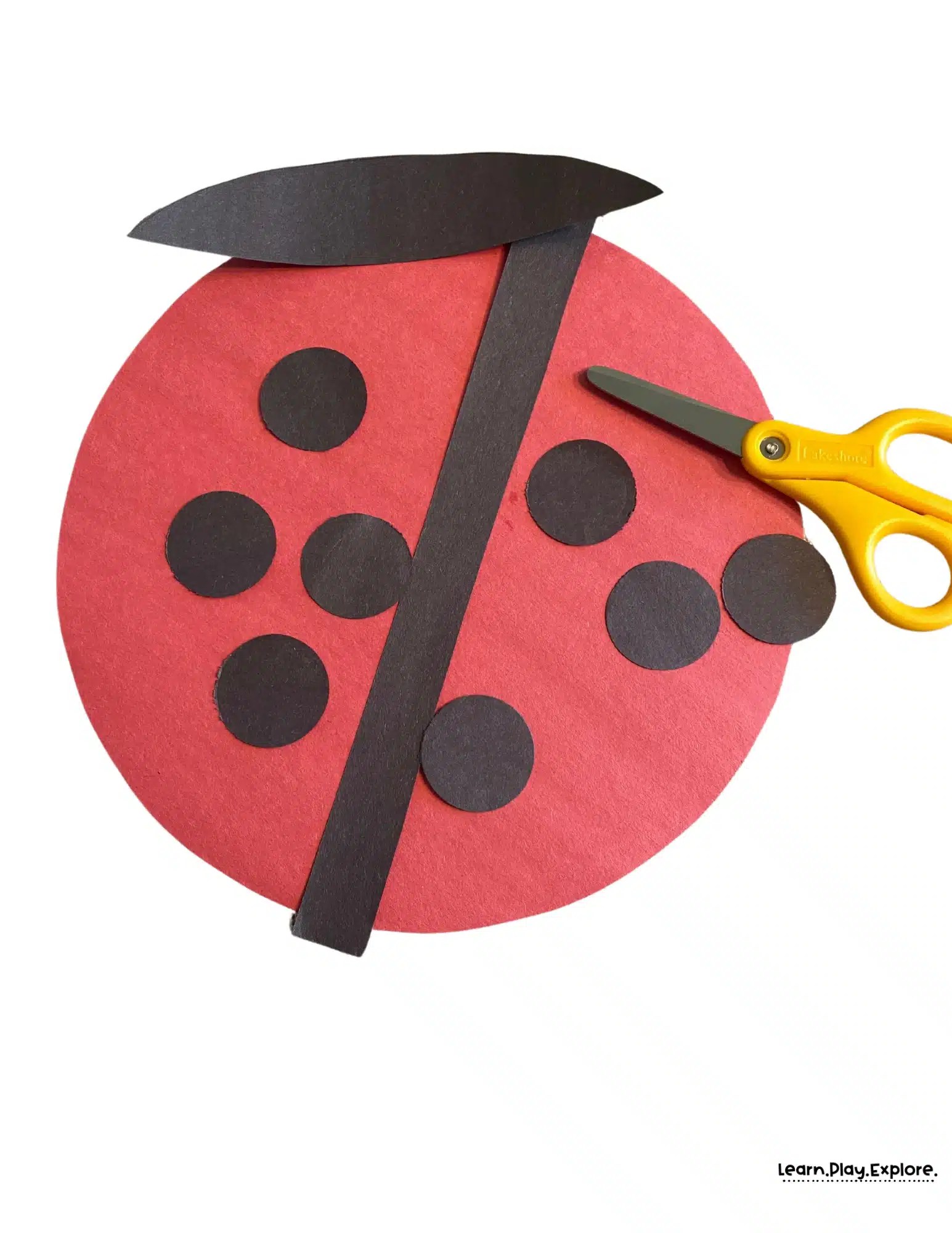red and black construction paper cut out with scissors to create a ladybug craft