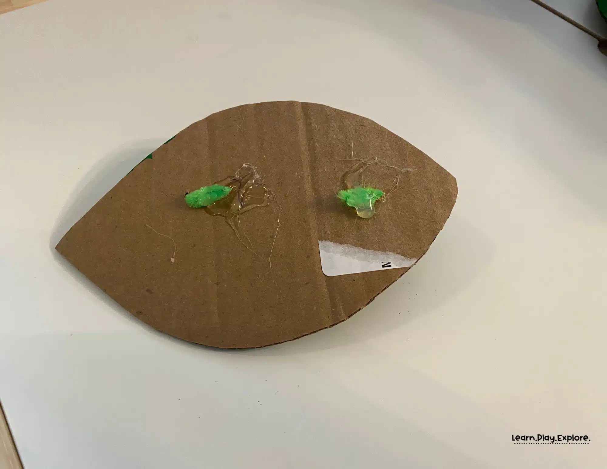 glue on back of cardboard to secure pipecleaner