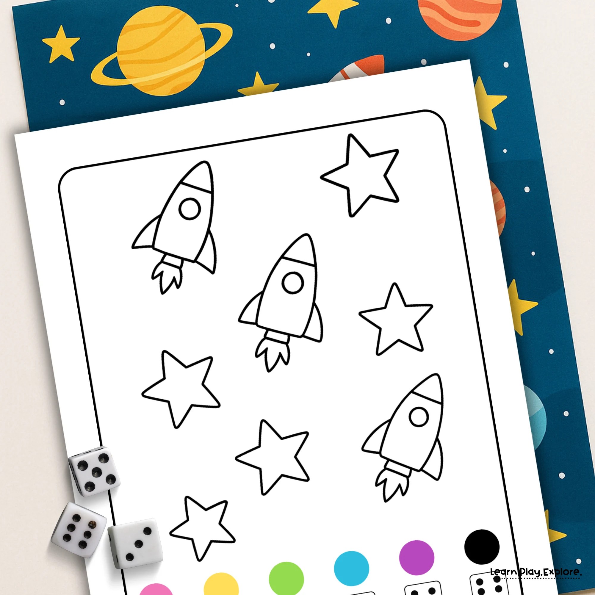 roll and color space printable with 3 dice and a fun rocket and star background. the paper under the space printable had stars and planets in blues yellows oranges