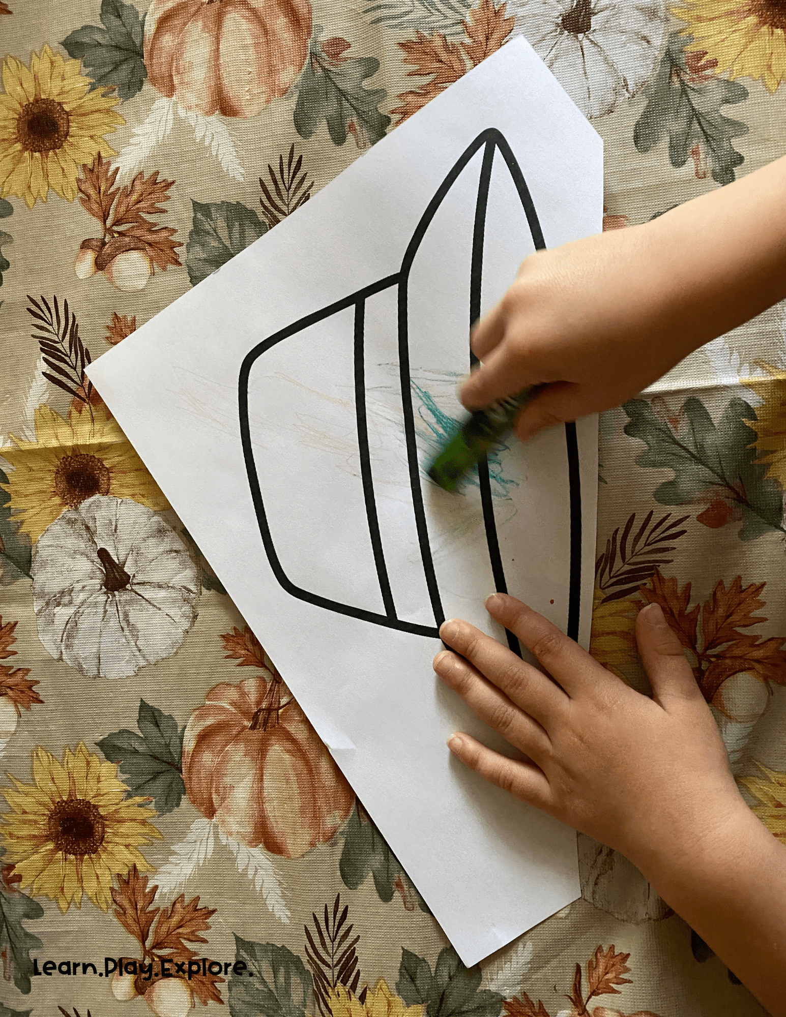 toddler coloring a hat green. hat outline on white paper. 