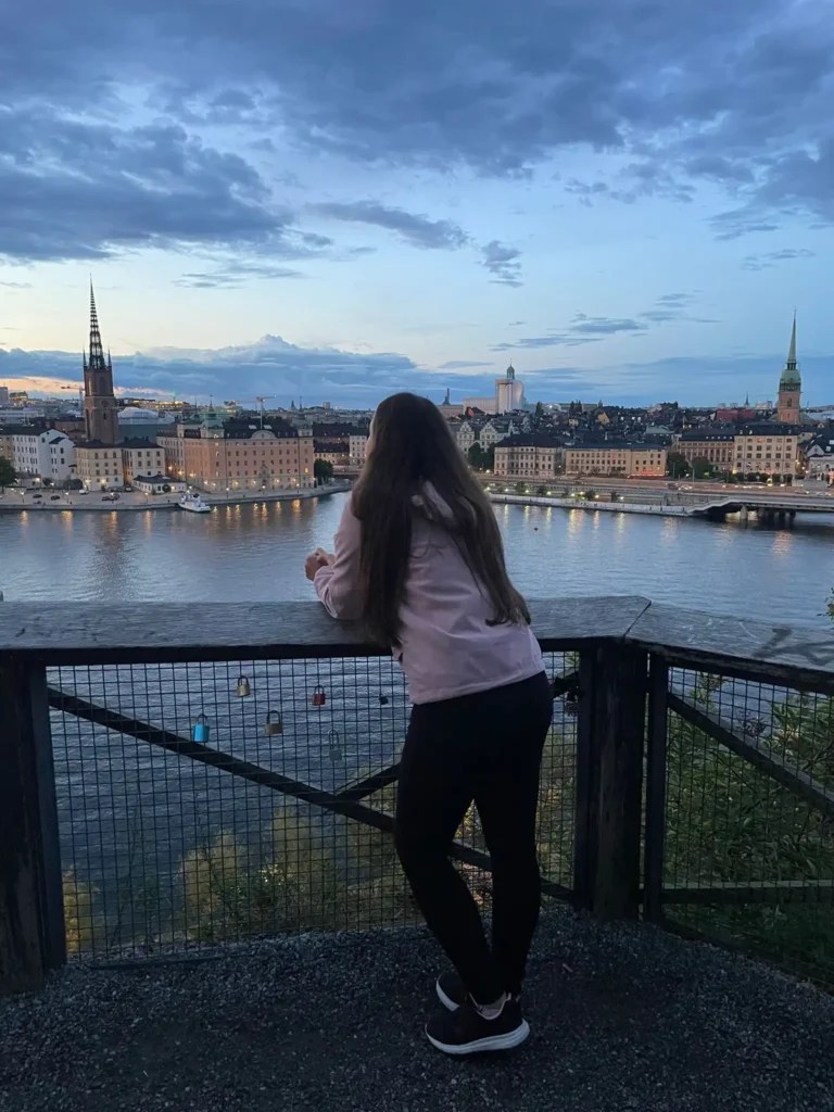 Yanitsa looking over the water and city skyline in Stockholm at sunset.