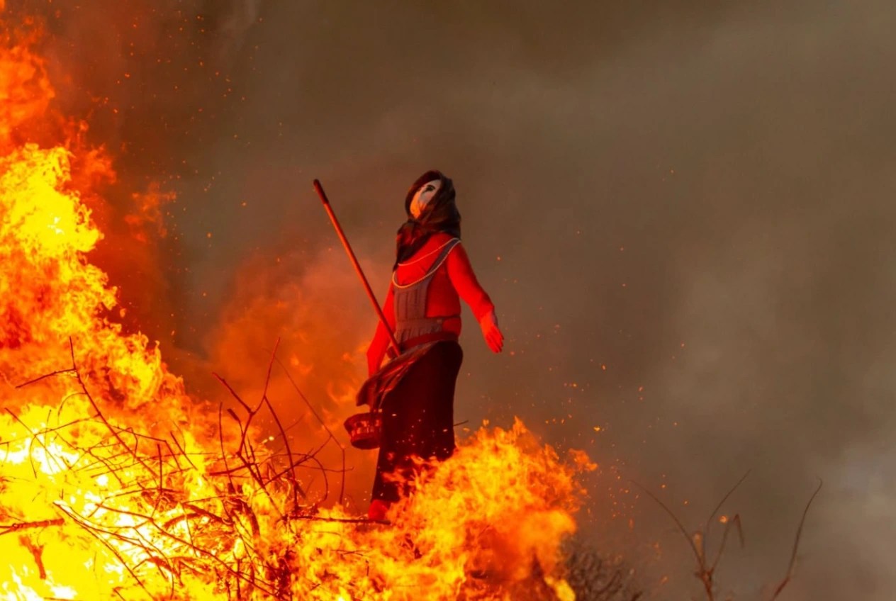 A straw witch figure burning on a Sankthansaften bonfire in Denmark, surrounded by flames and smoke