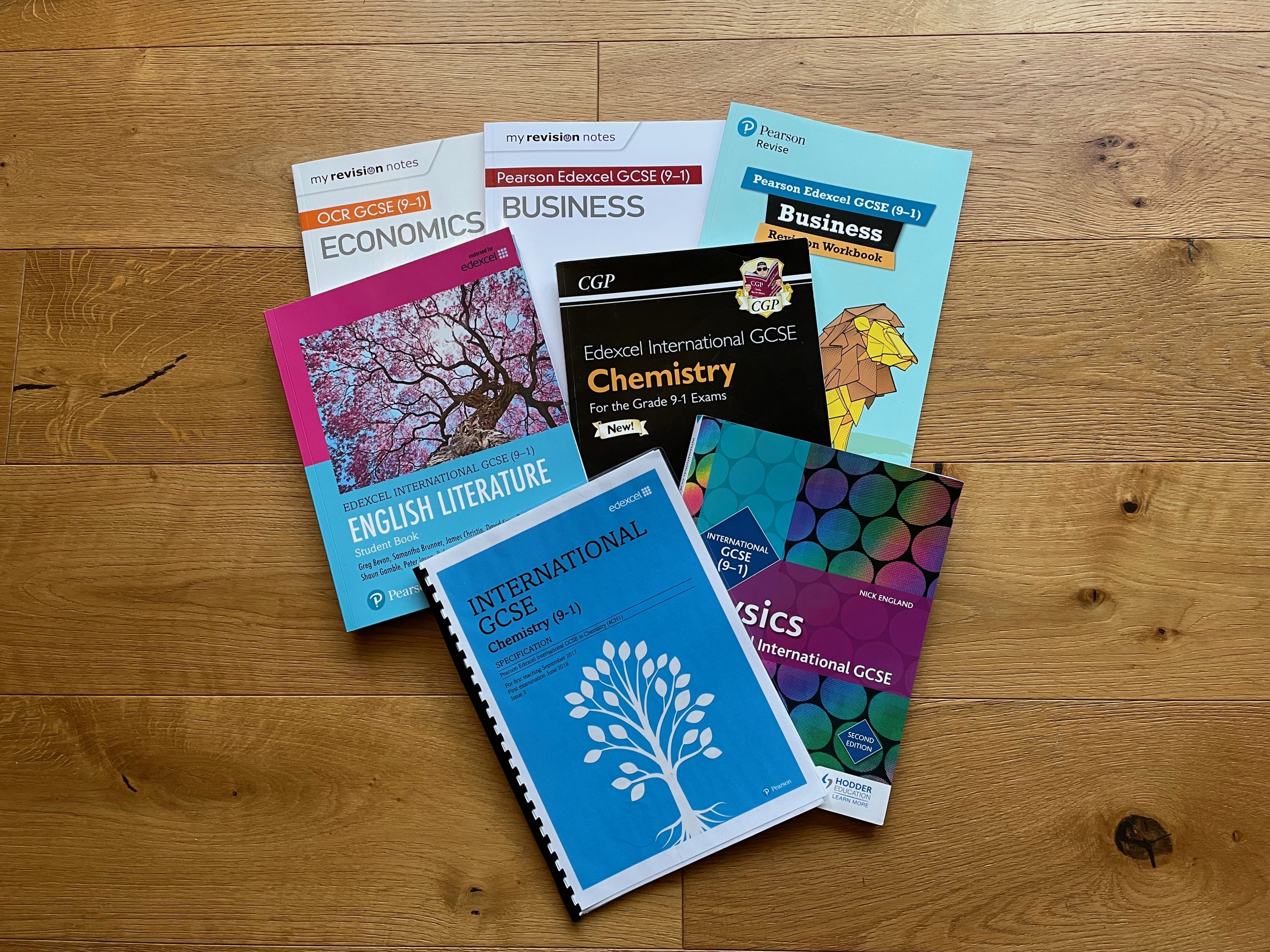 selection of GCSE textbooks lying on a wooden floor