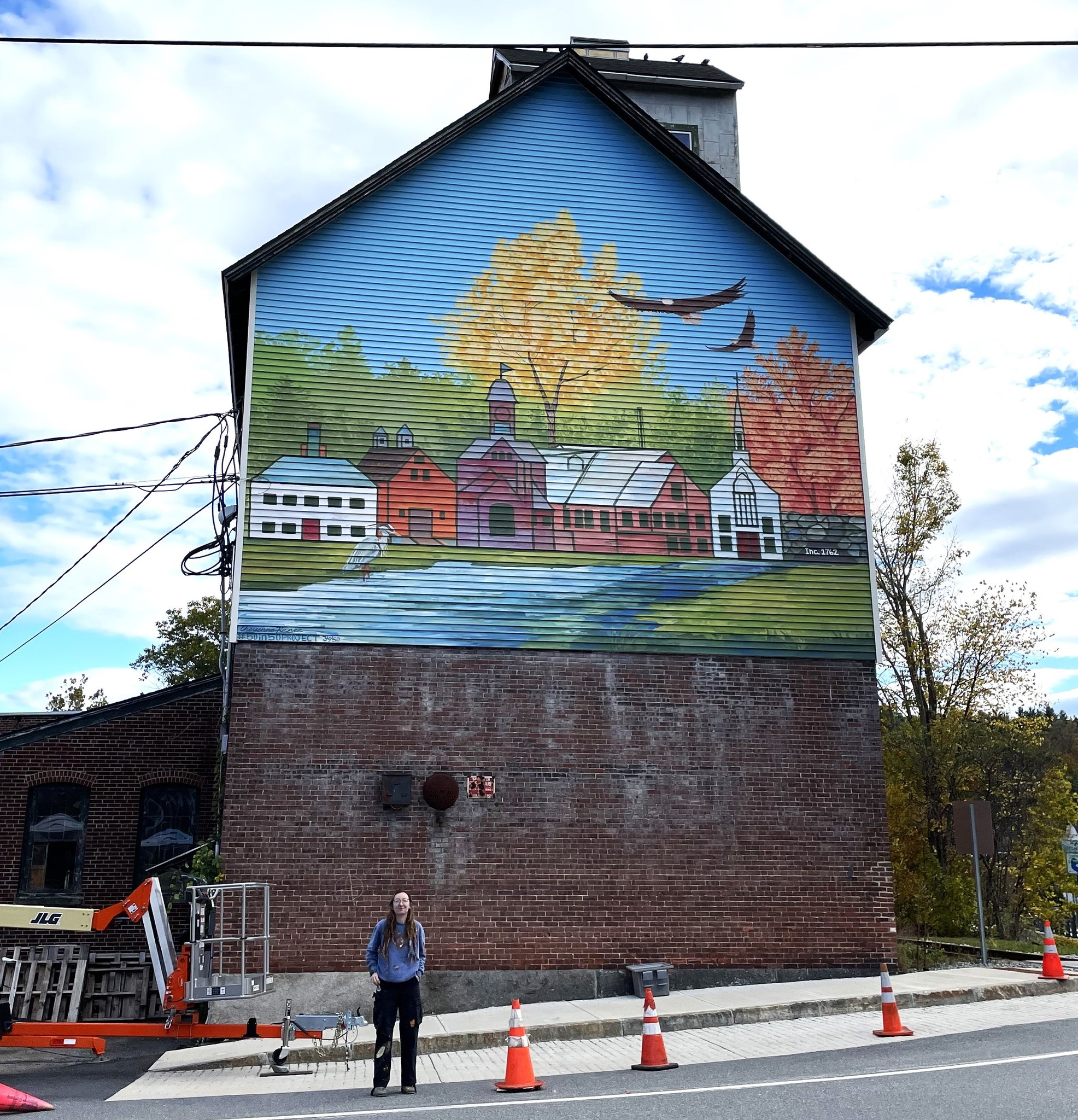 Cheyenne Renee in front of her completed mural on the Wilton Falls building. COURTESY