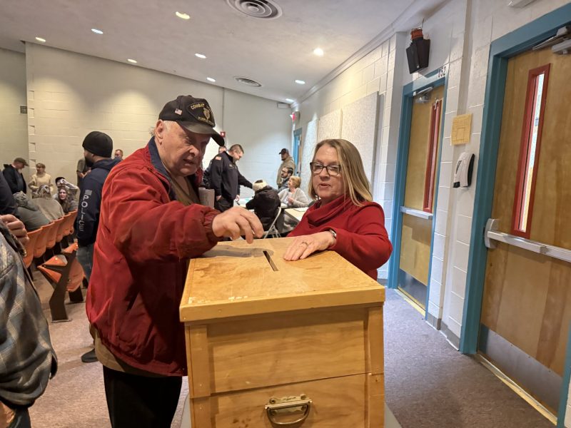 Ron Stanley casts a vote for a proposed amendment to the town budget at the ballot box, overseen by Deputy Moderator Carol Romeril, in February 2026. ASHLEY SAARI / Ledger-Transcript